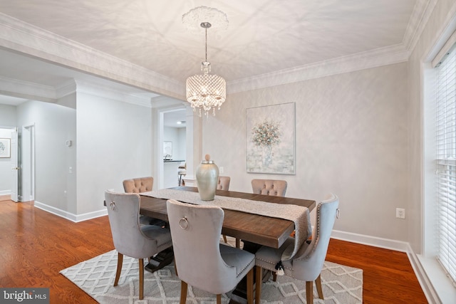 dining room featuring baseboards, crown molding, wood finished floors, and a chandelier