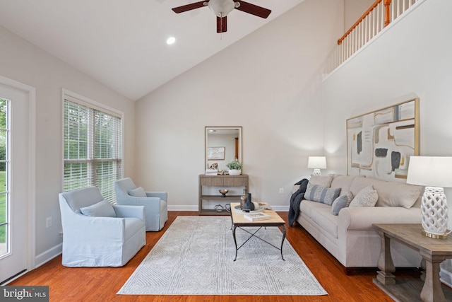 living room with high vaulted ceiling, ceiling fan, baseboards, and wood finished floors