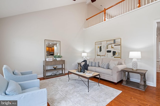 living area with high vaulted ceiling, baseboards, a ceiling fan, and wood finished floors