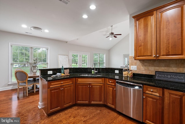 kitchen featuring a peninsula, wood finished floors, stainless steel dishwasher, and a sink