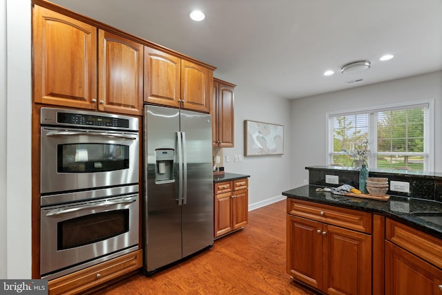 kitchen featuring dark stone counters, light wood-style flooring, recessed lighting, and appliances with stainless steel finishes