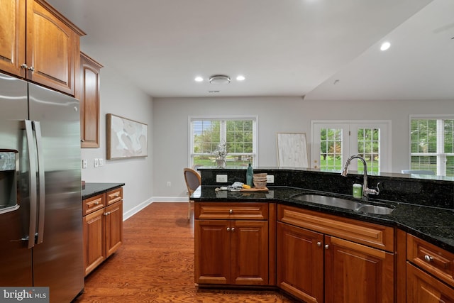 kitchen featuring dark stone counters, a sink, stainless steel fridge with ice dispenser, dark wood finished floors, and recessed lighting