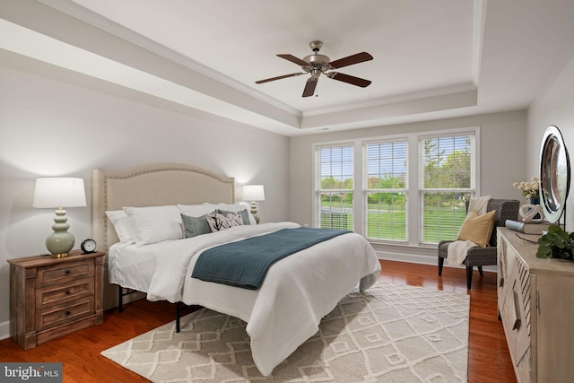 bedroom featuring ceiling fan, crown molding, wood finished floors, and a raised ceiling