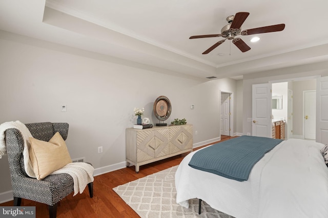 bedroom featuring a tray ceiling, wood finished floors, visible vents, ornamental molding, and baseboards
