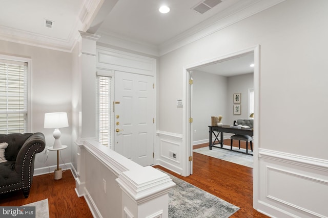 foyer featuring wood finished floors, visible vents, and crown molding