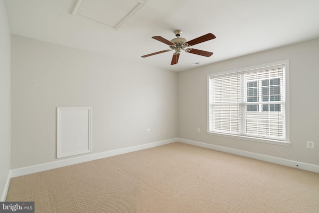 spare room with attic access, ceiling fan, baseboards, and light carpet