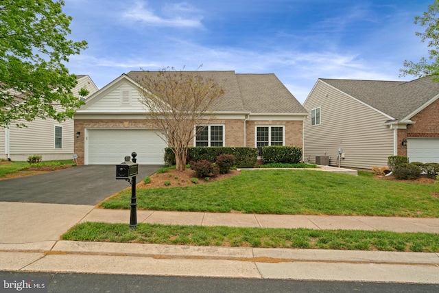 view of front of house with a garage, brick siding, a front yard, and aphalt driveway