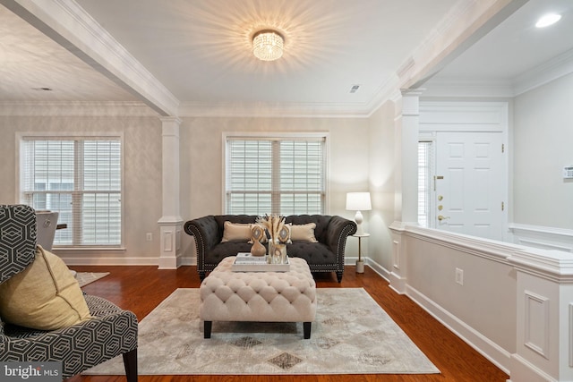 living area with plenty of natural light, decorative columns, wood finished floors, and crown molding