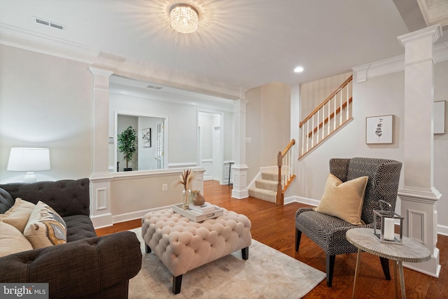 living area with wood finished floors, crown molding, ornate columns, and stairway