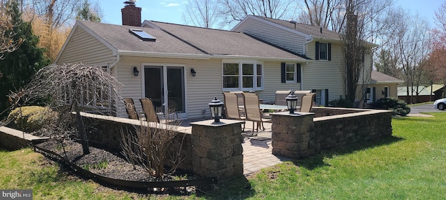 back of property featuring a lawn, a shingled roof, a patio area, and a chimney