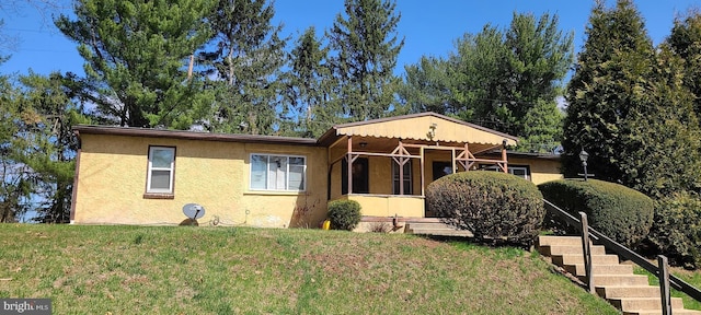 view of front of house with a front yard, stairway, and stucco siding