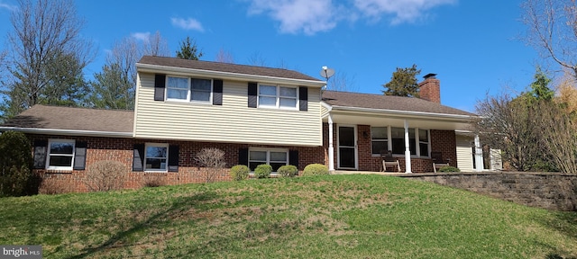 split level home featuring a chimney, brick siding, and a front lawn