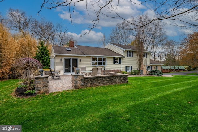 rear view of house with a chimney, a patio area, and a yard