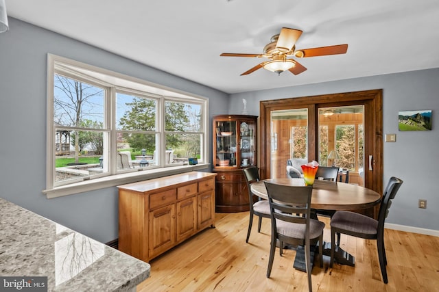 dining room featuring ceiling fan, plenty of natural light, light wood-style flooring, and baseboards