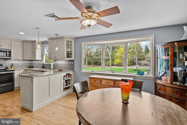 kitchen with glass insert cabinets, backsplash, stainless steel appliances, and pendant lighting