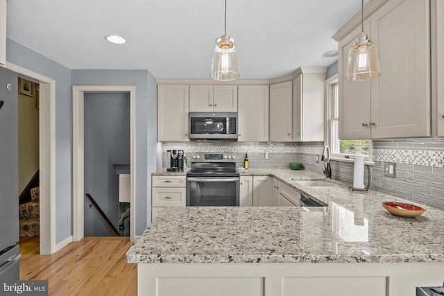 kitchen with light wood-style floors, stainless steel appliances, backsplash, and a sink