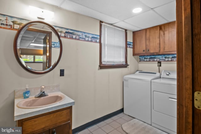 laundry area featuring light tile patterned floors, cabinet space, a sink, baseboards, and washer and clothes dryer