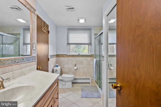 full bath featuring tile patterned floors, visible vents, a baseboard heating unit, and tile walls