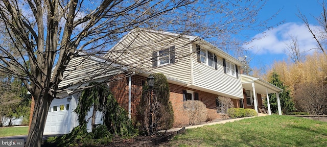 view of side of property with covered porch, a yard, and brick siding