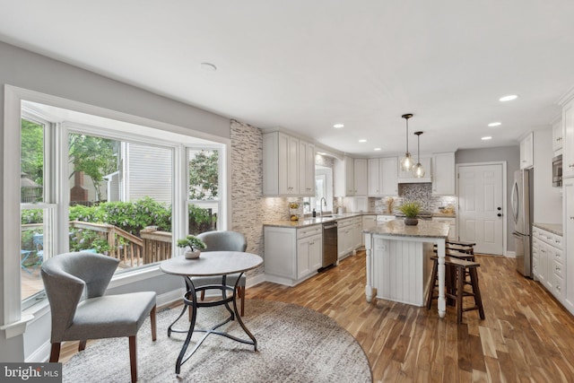13126 Pelmira Ridge Ct, Herndon, VA 20171 - kitchen featuring stainless steel appliances, a sink, a center island, light wood-type flooring, and tasteful backsplash