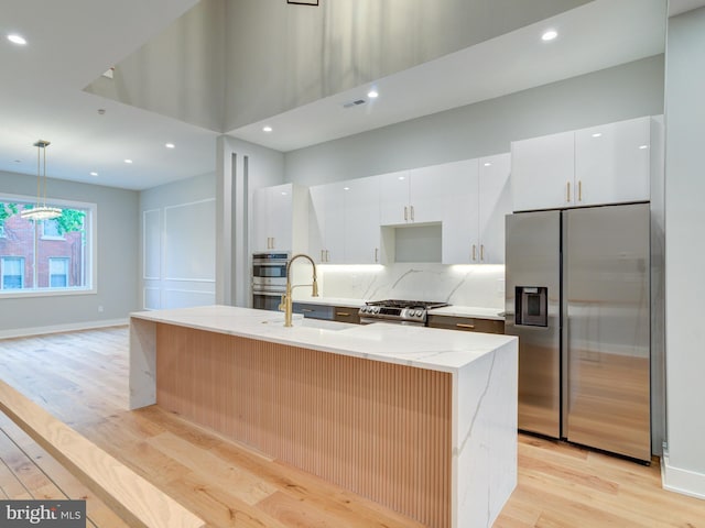1021 E Palmer St, Philadelphia, PA 19125 - kitchen featuring stainless steel appliances, a sink, light wood-style flooring, white cabinetry, and a center island with sink