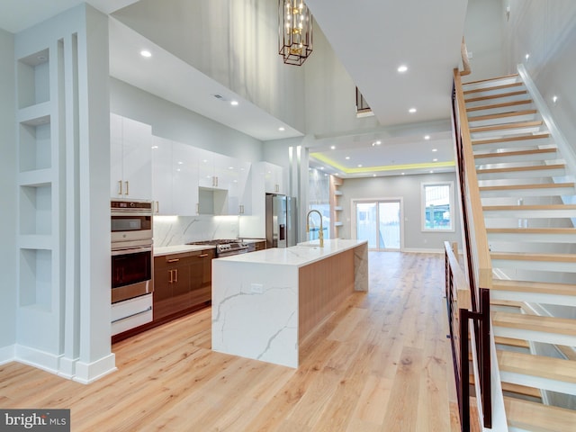 1021 E Palmer St, Philadelphia, PA 19125 - kitchen with modern cabinets, appliances with stainless steel finishes, white cabinets, light wood-type flooring, and a large island with sink