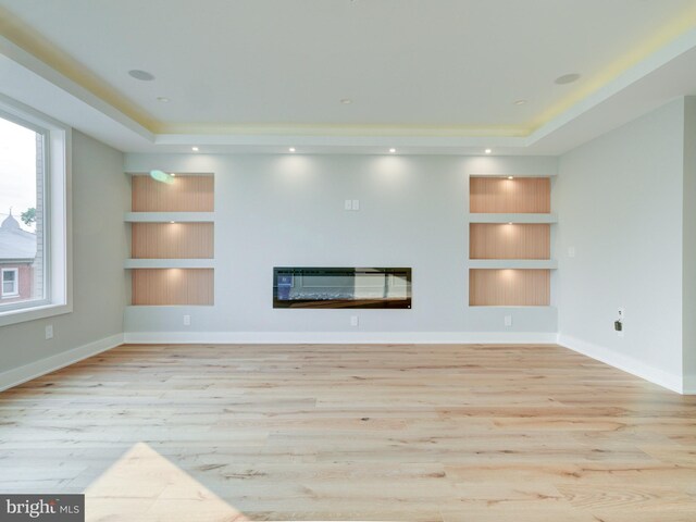 1021 E Palmer St, Philadelphia, PA 19125 - unfurnished living room featuring built in shelves, a raised ceiling, wood finished floors, and a glass covered fireplace