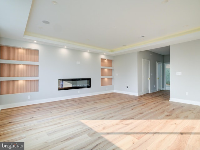 1021 E Palmer St, Philadelphia, PA 19125 - unfurnished living room featuring a tray ceiling, built in features, wood finished floors, a glass covered fireplace, and recessed lighting