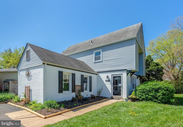 traditional-style home featuring brick siding, roof with shingles, and a front yard