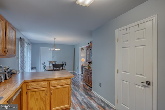 kitchen with pendant lighting, a peninsula, baseboards, dark wood finished floors, and a notable chandelier
