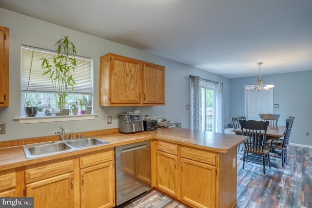 kitchen with stainless steel dishwasher, a peninsula, wood finished floors, light countertops, and a sink