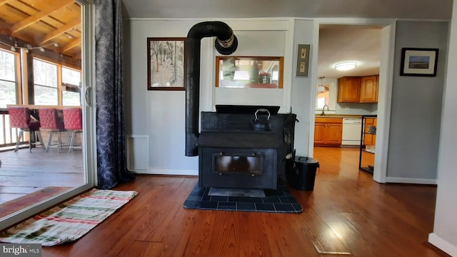 living area with baseboards, a wood stove, and wood finished floors