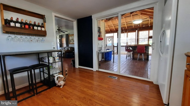 dining room featuring wood finished floors, visible vents, a bar, and ceiling fan