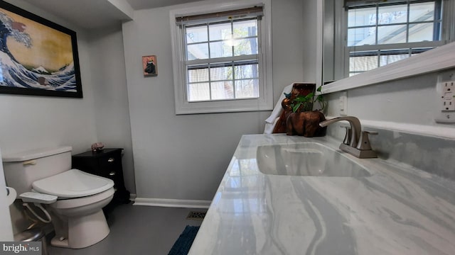 bathroom with visible vents, toilet, baseboards, and a sink