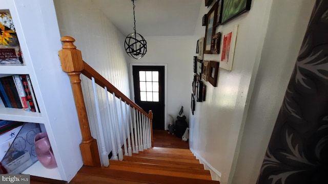staircase with wood finished floors and a notable chandelier