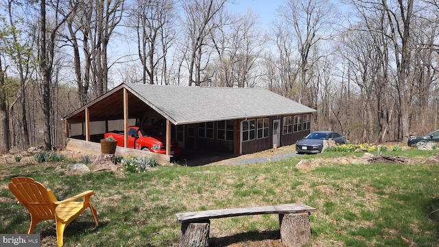 view of side of home with a shingled roof and a yard