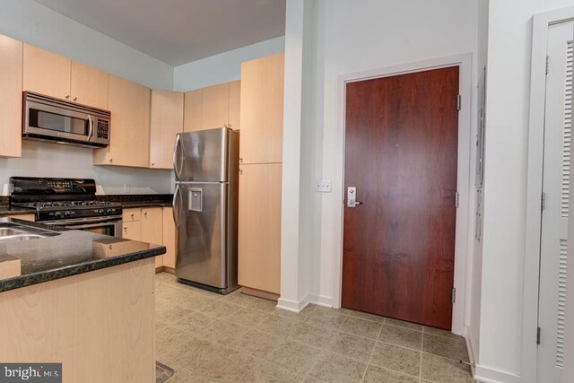1209 N Charles St N Unit 209, Baltimore, MD 21201 - kitchen with stainless steel appliances, dark stone counters, baseboards, and light brown cabinets