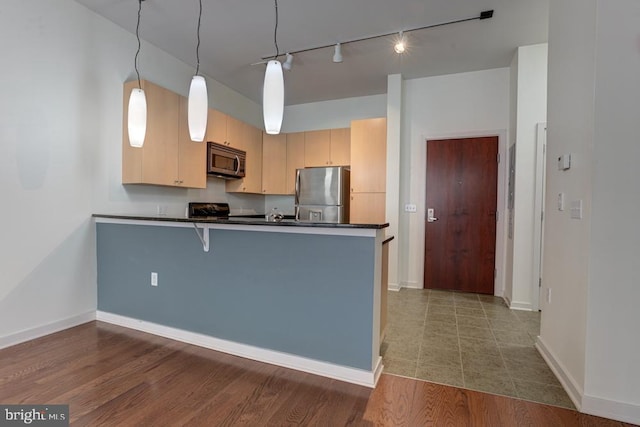 1209 N Charles St N Unit 209, Baltimore, MD 21201 - kitchen with stainless steel appliances, dark countertops, rail lighting, a peninsula, and baseboards