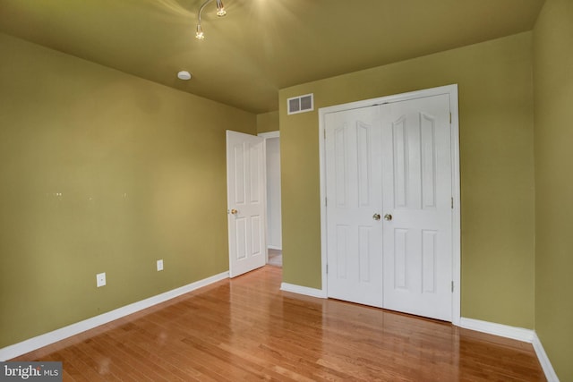 unfurnished bedroom with baseboards, wood finished floors, and a closet
