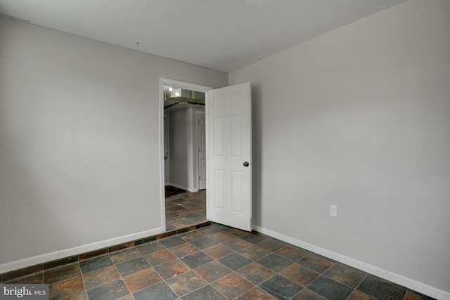 unfurnished bedroom with baseboards and stone finish floors