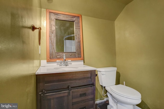 bathroom featuring toilet, vanity, baseboards, and lofted ceiling