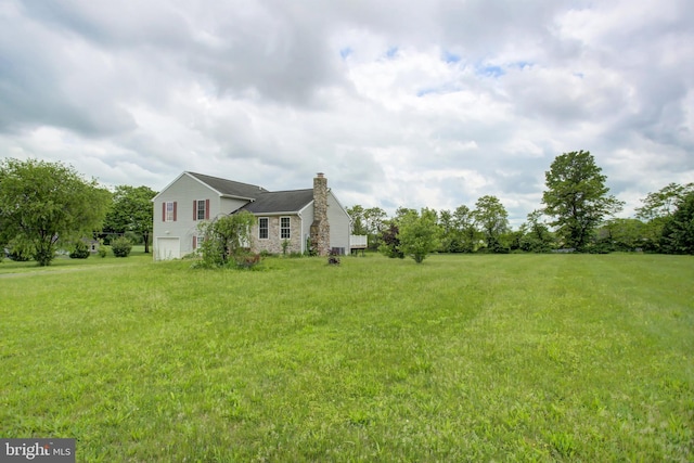 view of side of home featuring a chimney, a garage, and a yard