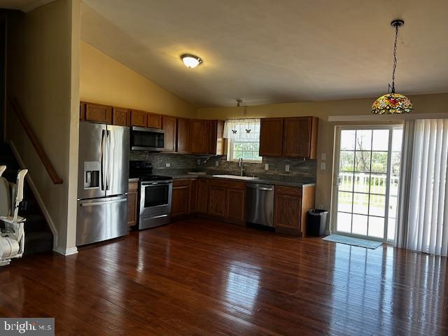 kitchen featuring appliances with stainless steel finishes, decorative backsplash, dark wood-style flooring, and vaulted ceiling