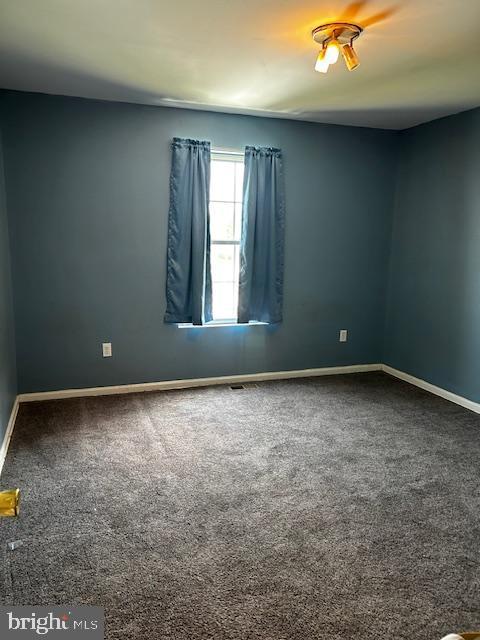 spare room with baseboards and carpet floors