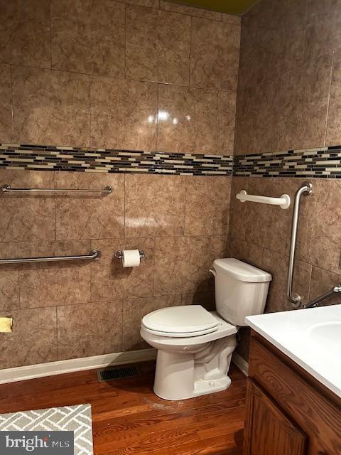 bathroom with wood finished floors, toilet, and vanity
