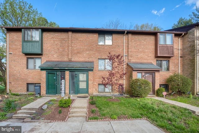 multi unit property featuring a front yard and brick siding