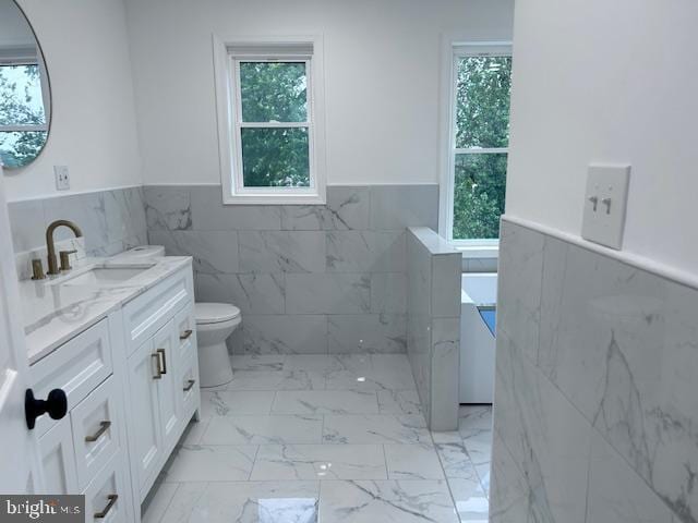580 Bath St, Bristol, PA 19007 - full bathroom featuring tile walls, wainscoting, vanity, plenty of natural light, and marble finish floors