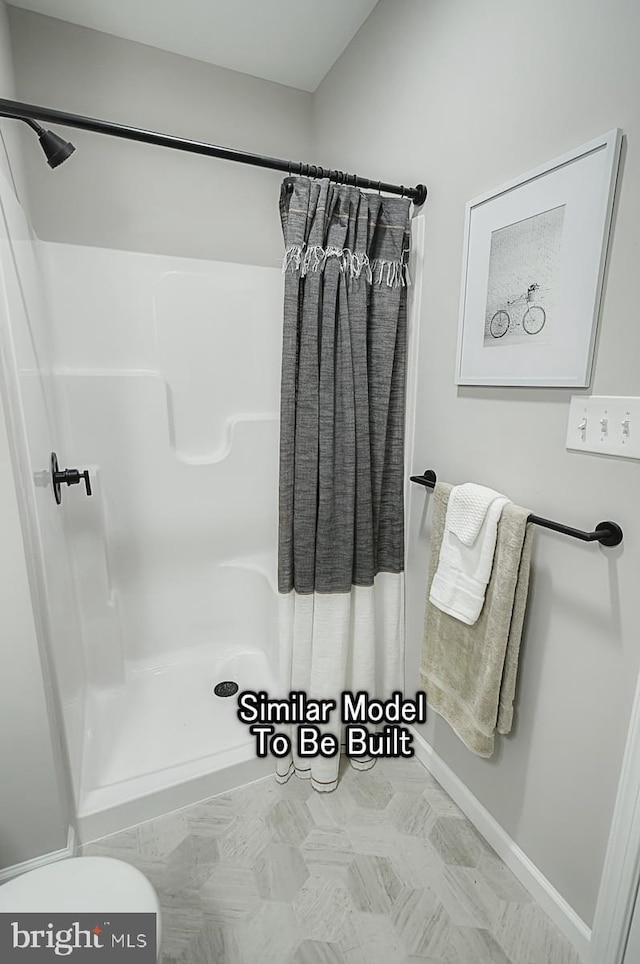 full bath featuring a shower stall, baseboards, and toilet