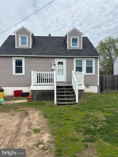 rear view of house featuring fence, a wooden deck, and a lawn