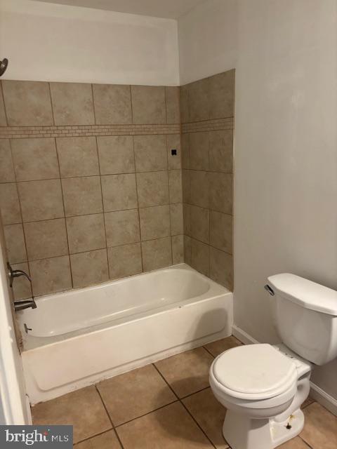 bathroom featuring toilet, tile patterned floors, baseboards, and shower / bathtub combination